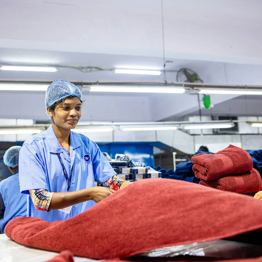 Nhân viên cùng hàng dệt trong xưởng, minh họa bối cảnh theo dõi lượng và đơn vị sản phẩm